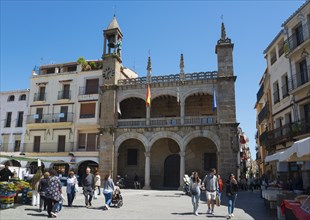 Lively square with historic building, clock tower and many people in sunny weather, town hall,