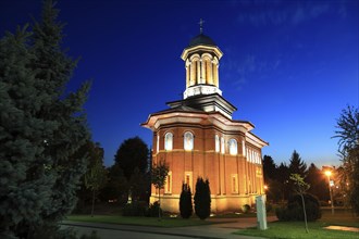 Illuminated church at night with a high tower, blue sky and visible windows. Craiova, Krajowa,