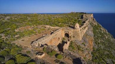 Drone shot, An ancient fortress ruin running along an overgrown cliff overlooking the sea, Venetian