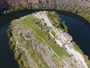 Historic ruin on a rocky hill with river in the background and lush vegetation, aerial view, gorge,