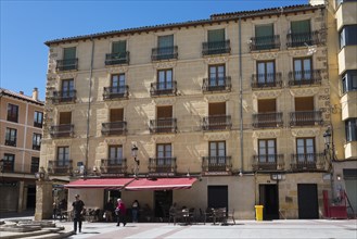 Historic building with balconies and shaded terrace, bright sunshine and clear sky, Plaza el Rosel,