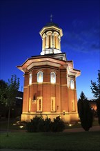 Illuminated church at night with a high tower, blue sky and visible windows. Craiova, Krajowa,