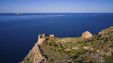 Drone shot, A historic ruin on a cliff overlooking the blue Mediterranean Sea to the horizon,