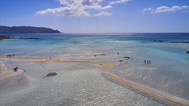 Clear blue sea with sandbanks and an island in the background. Few people enjoy the quiet