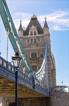 The historic Tower Bridge with towering structures and blue lower section under a clear sky,