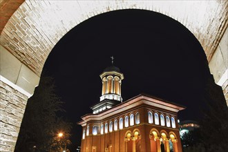 Illuminated church at night with a high tower, blue sky and visible windows. Craiova, Krajowa,