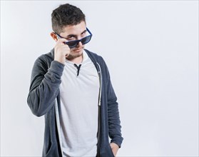 Handsome guy lowering his glasses looking at the camera. Attractive young man in glasses looking at