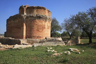 Roman ruins of Milreu, near Estoi, Algarve, Portugal, Old round brick wall, surrounded by trees and