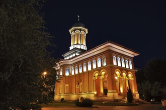 Illuminated church at night with a high tower, blue sky and visible windows. Craiova, Krajowa,