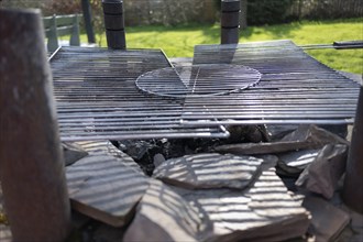 Outdoor barbecue, barbecue from an old well, two used grill grates lying on top, burnt coal