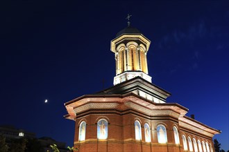 Illuminated church at night with a high tower, blue sky and visible windows. Craiova, Krajowa,