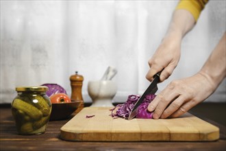 Unrecognizable man cutting red cabbage in the kitchen