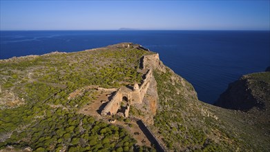 Drone shot, An old fortress ruin on a cliff above the vast Mediterranean Sea, surrounded by