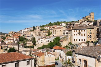 Historic town on a hill with houses and green vegetation under a blue sky, city view, Sepúlveda,