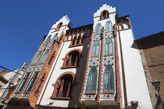 An impressive building with an elaborate brick façade and beautiful windows under a clear blue sky,