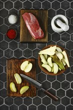 Overhead view of sliced apples and pears laid out on a chopping board next to the duck breast