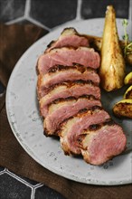 Close-up view of seared duck breast with golden-brown roasted potato wedges