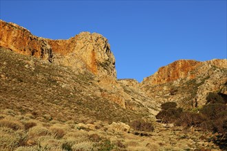 Morning light, Sunny landscape of vegetation-rich hills and rocks under a clear blue sky,
