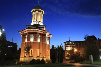 Illuminated church at night with a high tower, blue sky and visible windows. Craiova, Krajowa,