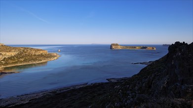 Photograph of a rocky island in a calm blue sea under a clear blue sky, Gramvoussa, Gramvoussa