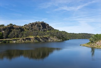 River with large rock in the background and blue sky, landscape characterised by natural wonders,