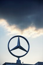 Symbolic image, Dark clouds at Mercedes, Mercedes-Benz logo in front of a sunset sky with clouds