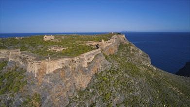 Drone shot, An old fortress ruin on a rocky cliff overlooking the deep blue sea, Venetian sea