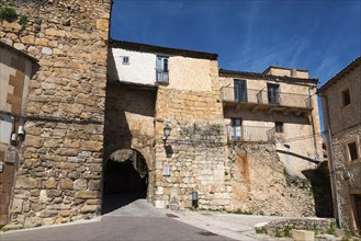 Medieval alley with historic buildings and a stone arch and a sunny blue sky, Puerta del Azogue or