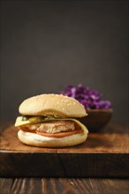 Close-up view of homemade hamburger with red cabbage salad on wooden board