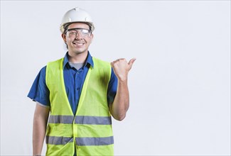 Portrait of engineer man pointing to side isolated. Smiling engineer man pointing side isolated