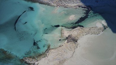 Drone shot, aerial view shows clear turquoise water, sandy beach and rocks in natural coastline,