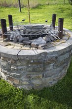 Outdoor barbecue, barbecue from an old well, two used grill grates lying on top, four metal pipes