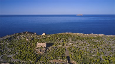 Drone shot, ruins on cliffs by the sea with sweeping views and lush vegetation to the horizon,