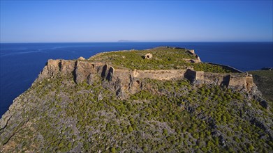 Drone shot, An old fortress perched on a green, rocky hill with sweeping sea views and surrounding