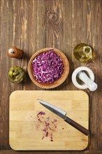 Overhead view of kitchen tabletop with red cabbage and pickled cucumbers