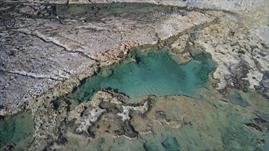 Drone shot, close-up of rocks and turquoise water with clear cracks and geological shapes,