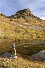 Lake Augstsee and the Atterkogel mountain on the Loser. A hiker stands on the shore. Autumn, good