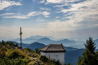 Summit cross and chapel of the Spitzstein, behind the silhouettes of the Loferer and Chiemgau Alps,