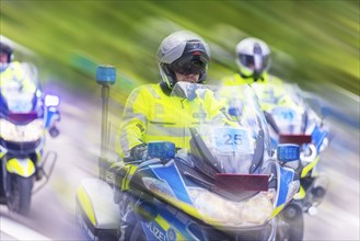 Police on motorbikes in bright safety clothing in motion with a blur effect on a street, Stuttgart,