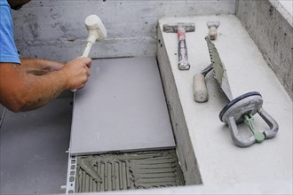 Tiler hands working on a new house entrance, local and professional handyman applying tiles to the