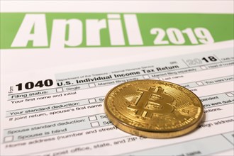 Bitcoin with 1040 income tax form for 2018 showing tax day for filing on April 15