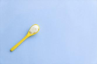 Spoon with sugar close-up on a light blue background