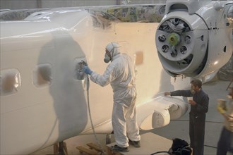 Tradesman sprays the fuselage on a Dornier 228 aircraft