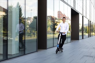 Young and casual business man riding electric scooter in the city