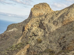 Rocky mountain with a view of the coast and a cloudy sky, tenerife, canary islands, spain