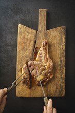 Man cutting a seared dry aged rib eye steak