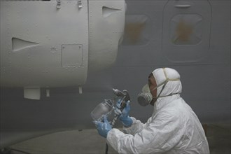 Tradesman sprays the engine on a Dornier 228 aircraft