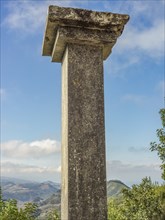 Old column against a background of cloudy sky and hilly landscape, tenerife, canary islands, spain