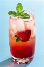 Glass of strawberry drink with ice cubes and mint leaves on a seamless blue background. A single