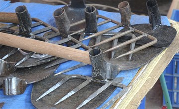 A street vendor sells handcrafted agricultural and gardening tools